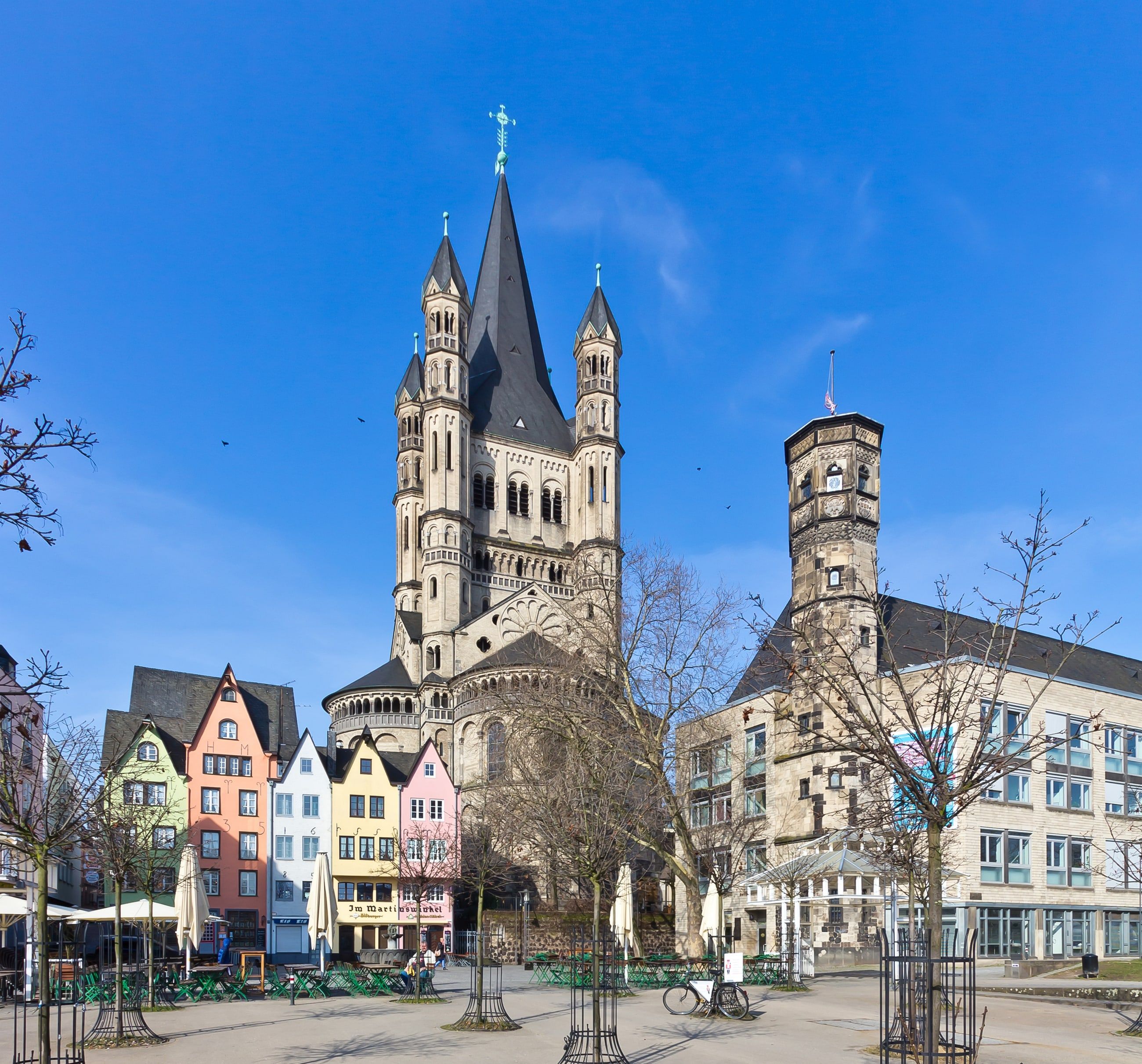 Bunte Giebelhäuser am Fischmarkt in der Kölner Altstadt, dahinter die romanische Kirche Groß St. Martin.