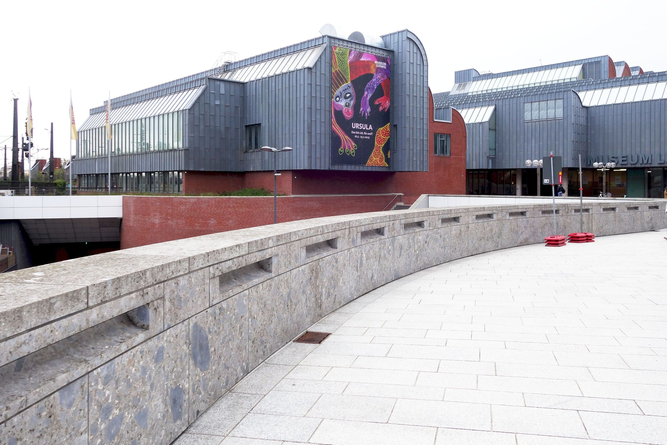 Das Museum Ludwig in Köln mit seinen gezackten Sheddächern, davor ein geschwungener Fußweg.