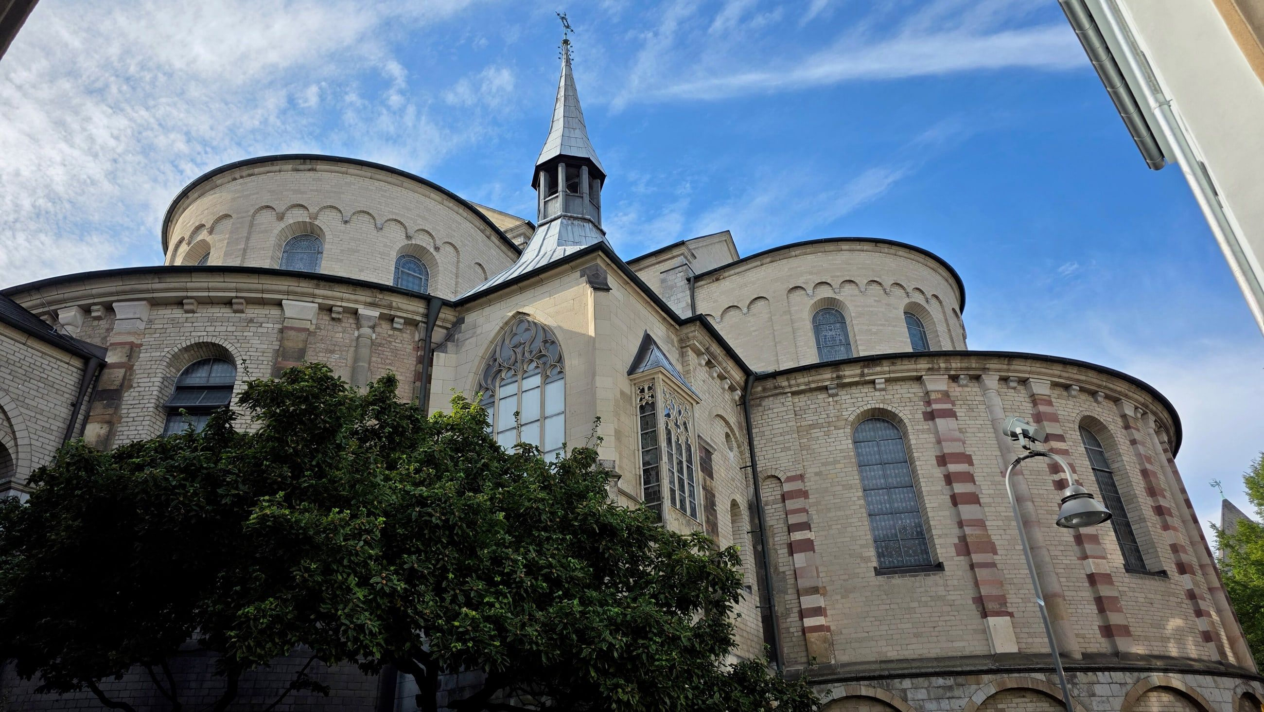 Die Dreikonchen-Apsis der romanischen Kirche St. Maria im Kapitol in Köln vor blauem Himmel.